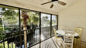 A room with a large window, a ceiling fan, and a table with chairs. - Beach getaway overlooking tropical lagoon. (Saint Augustine)