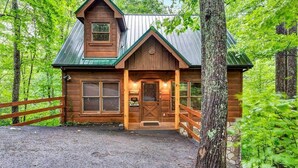 A rustic cabin with a wooden exterior, a metal roof, and a front porch. - Fallin' in Love: Lose Your Heart in the Smokies (Sevierville)
