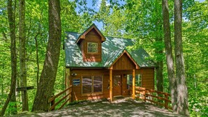 A wooden cabin with a porch, surrounded by trees. - Fallin' in Love: Lose Your Heart in the Smokies (Sevierville)