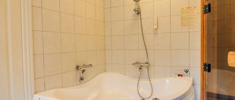 A bathroom with a freestanding bathtub, a showerhead, and a toilet.