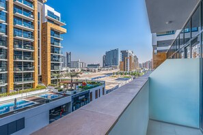 A modern high-rise building with multiple balconies, a rooftop pool, and a view of the cityscape.
