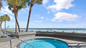 A swimming pool with a view of the ocean, surrounded by palm trees and a clear sky. - Garden City Beach Oceanfront Condo 306 | Rising Tides Properties Rental (Murrells Inlet)