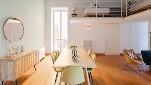 A modern room with a wooden dining table, green chairs, a round mirror, and a bunk bed with a ladder. - Elegant apartment with patio at Piazza Navona (Roma)