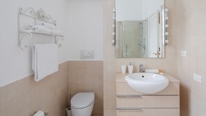 A modern bathroom with a toilet, sink, vanity, and a mirror with lights. - Elegant apartment with patio at Piazza Navona (Roma)