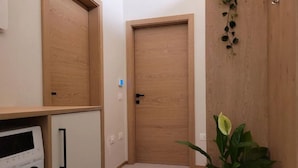 A laundry room with a washing machine, a wooden door, and a potted plant. - Magnolia LevicoGround floor apartment in the center of Levico Terme (Levico Terme)