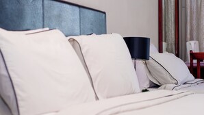 A neatly made bed with white linens and a dark-colored headboard.