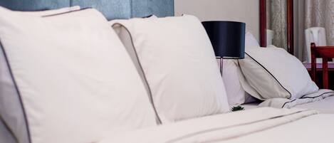 A neatly made bed with white linens and a dark-colored headboard.