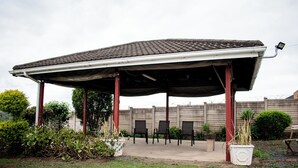 A covered outdoor seating area with chairs and potted plants.