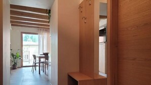 A hallway with a wooden bench, a dining area with a table and chairs, and a view of the outside. - Magnolia LevicoApartment with terrace in the center of Levico Terme (Levico Terme)