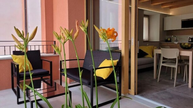 A modern living space with a balcony, a dining area, and a kitchen. - Magnolia LevicoApartment with terrace in the center of Levico Terme (Levico Terme)