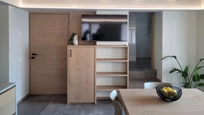 A modern kitchen with wooden cabinetry, a built-in TV, and a dining area with a table and chairs. - Magnolia LevicoApartment with terrace in the center of Levico Terme (Levico Terme)