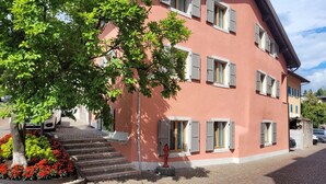 A multi-story building with a red facade, a tree in front, and a fire hydrant on the ground.