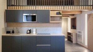 A modern kitchen with dark cabinets, a built-in oven, and a marble countertop.