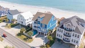 A beachfront property with a large house featuring multiple balconies and a swimming pool.