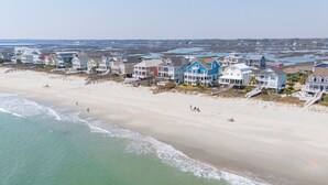A beachfront property with multiple houses, a sandy beach, and a view of the ocean.