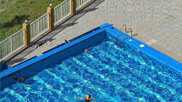 A rectangular swimming pool with a tiled deck surrounding it. - IvyRose Luxury Apartment 1 (Kampala)