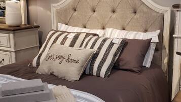 A neatly made bed with striped bedding and a tufted headboard.