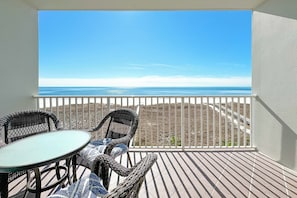 Un balcón con mesa y sillas, con vistas a la playa y al océano.