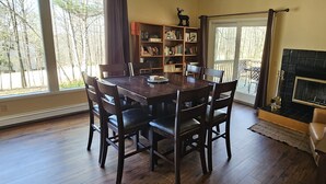 A dining room with a wooden table and chairs, a bookshelf, and a fireplace. - Two bedroom + loft near Lake Leelanau. Fire pit, W/D, WIFI (Lake Leelanau)