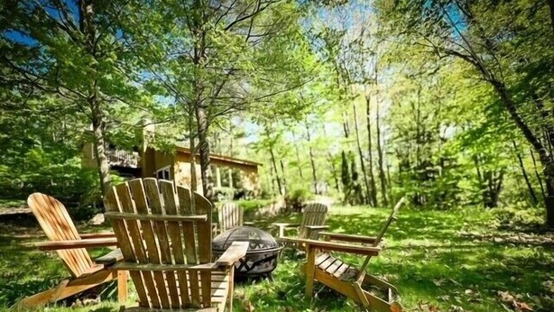 A rustic cabin with two Adirondack chairs in a forest setting. - Two bedroom + loft near Lake Leelanau. Fire pit, W/D, WIFI (Lake Leelanau)