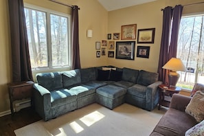 A living room with a sectional sofa, a lamp, and framed pictures on the wall.