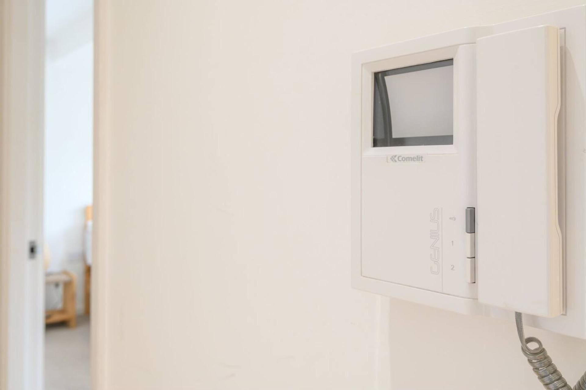 A white electrical panel with a Comelit brand label, a visible switch, and a cable connected to it.