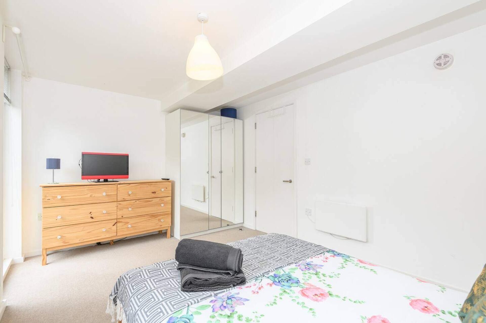 Un dormitorio con una cama, un aparador de madera, un televisor y un armario.