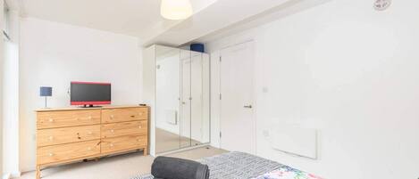 Un dormitorio con una cama, un aparador de madera, un televisor y un armario.