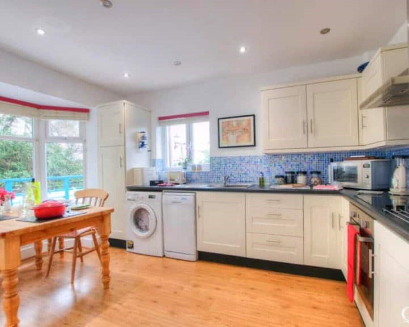 A compact kitchen with a washing machine, a microwave, and a dining area with a table and chairs.