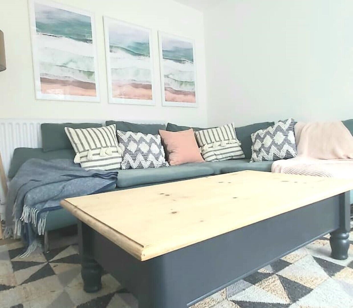 A living room with a sofa, a coffee table, and three framed artworks on the wall.