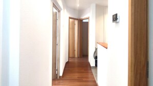 A narrow hallway with wooden flooring and white walls.