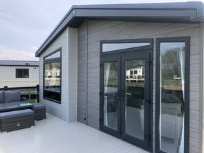 A modern house with a deck, large sliding glass doors, and a grey exterior. - 7 Guests - 3 Bedrooms - Pool - Balcony - Parking (Grange-over-Sands)