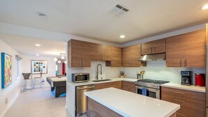 A modern kitchen with wooden cabinets, stainless steel appliances, and a central island.