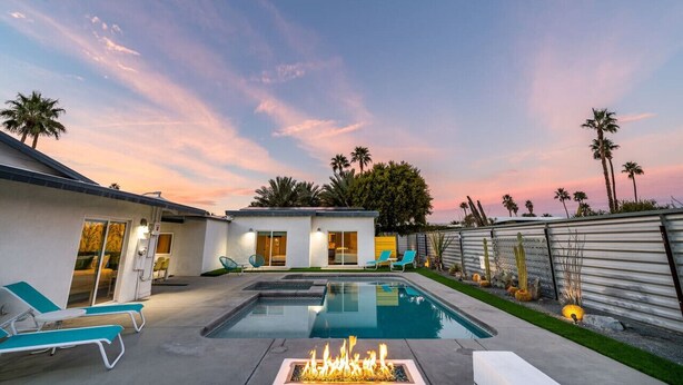 A modern house with a swimming pool, outdoor seating, and a fire pit.