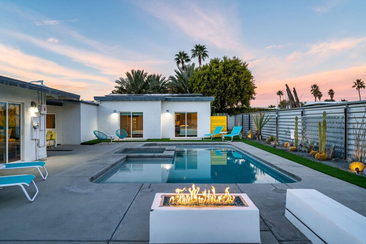 Une maison moderne dotée d’une piscine, d’un espace salon extérieur et d’un foyer.