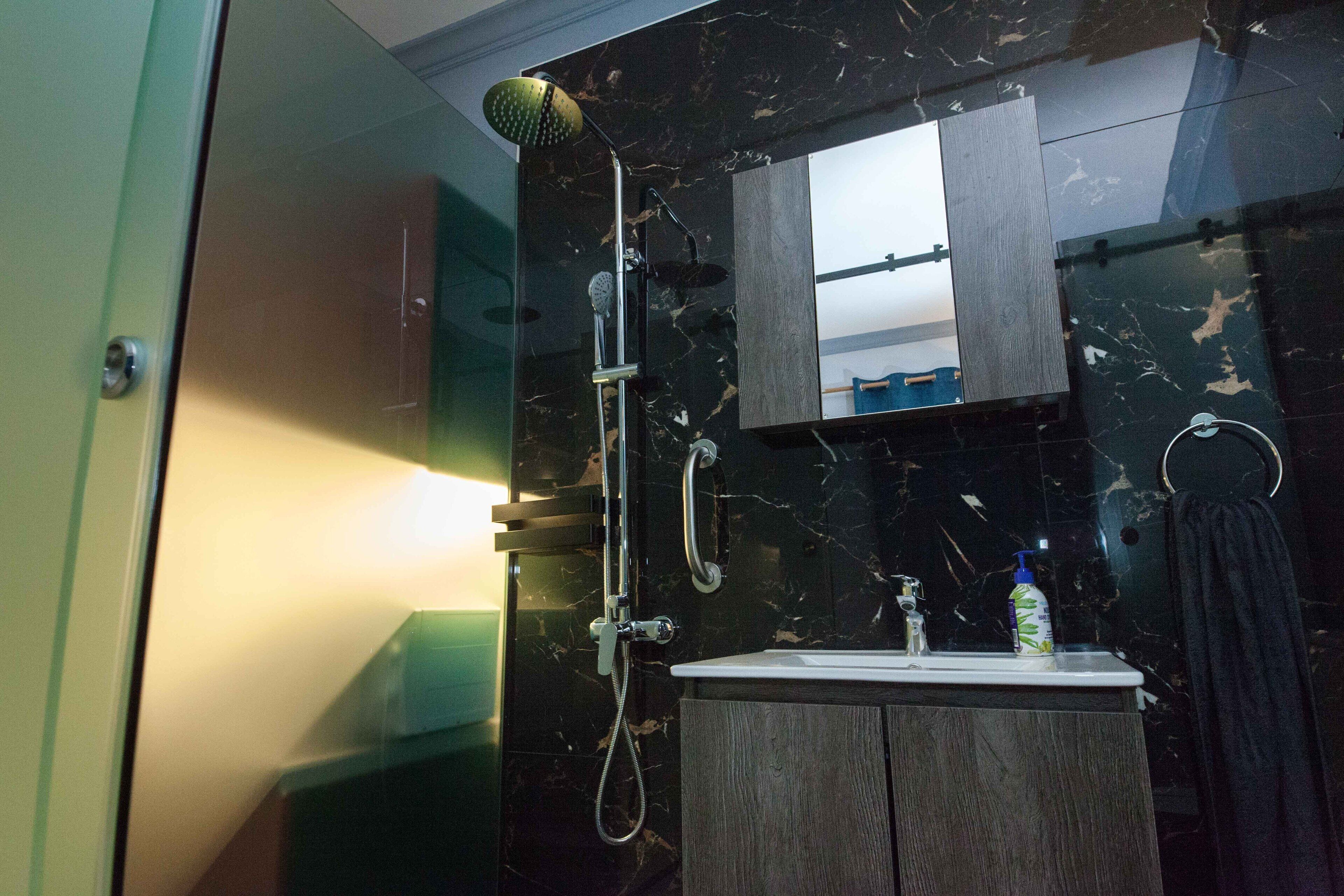 Een moderne badkamer met een douche, wastafel en spiegel.