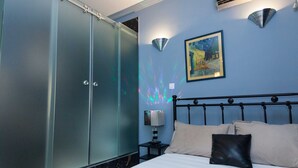 Quarto com cama, mesa de cabeceira, luminária, quadro e guarda-roupa.