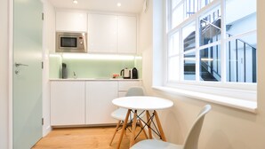 A modern kitchen with white cabinets, a microwave, and a window with a view of a staircase. - Sale Place Serviced Apartments by Concept Apartments (London)