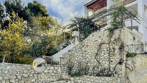 Paredes de pedra, um espelho circular, um edifício branco com telhado vermelho e vegetação.