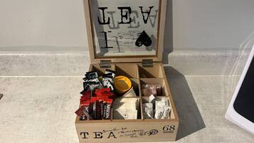 Une boîte en bois étiquetée « THÉ », comportant des compartiments contenant différents types de thé, et une plaque encadrée portant l’inscription « LEV I ».