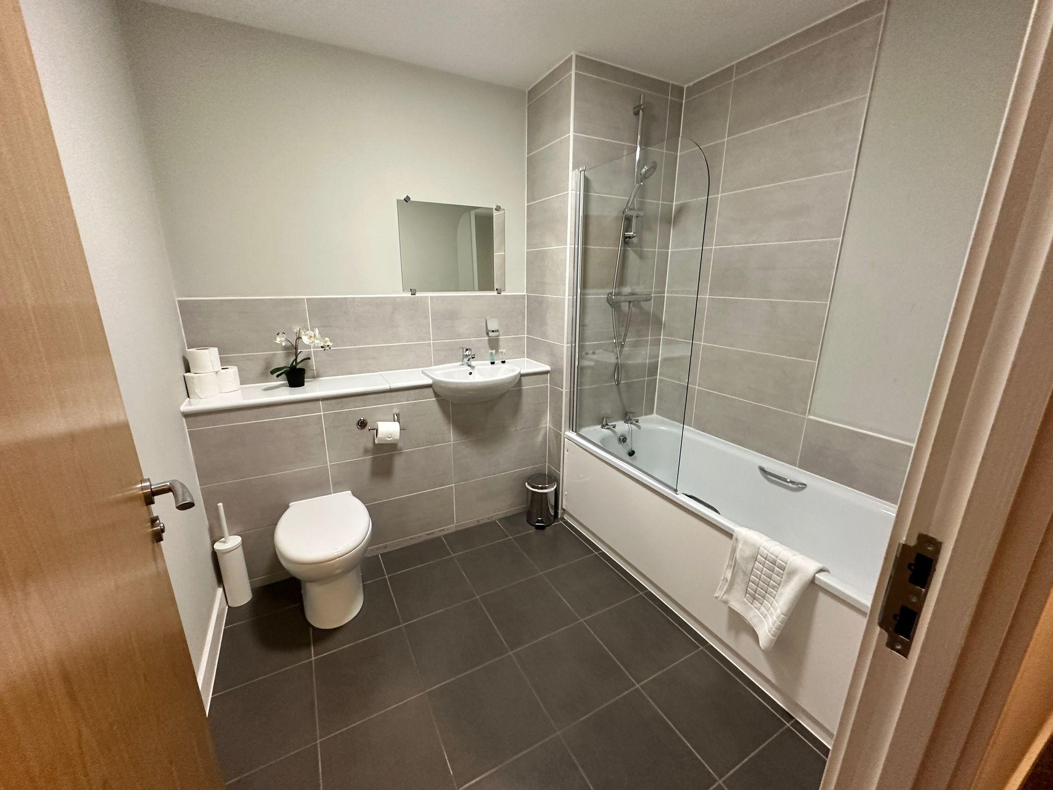 A modern bathroom with a toilet, sink, and shower.