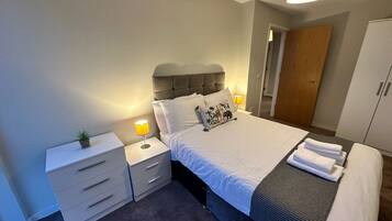 Un dormitorio con cama, mesitas de noche, armario y puerta.