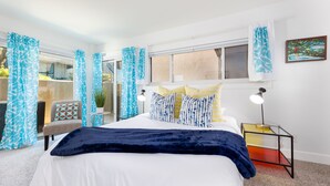 A bedroom with a bed, a chair, a nightstand, and a window with curtains.