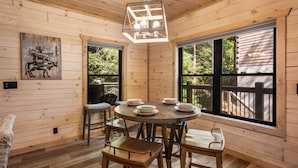 A wooden interior with a round dining table, six chairs, and a hanging light fixture. - Haven 2 Bedroom Cabin by RedAwning (Gatlinburg)
