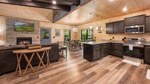 A spacious living area with a fireplace, a large TV, and a dining table. - Haven 2 Bedroom Cabin by RedAwning (Gatlinburg)