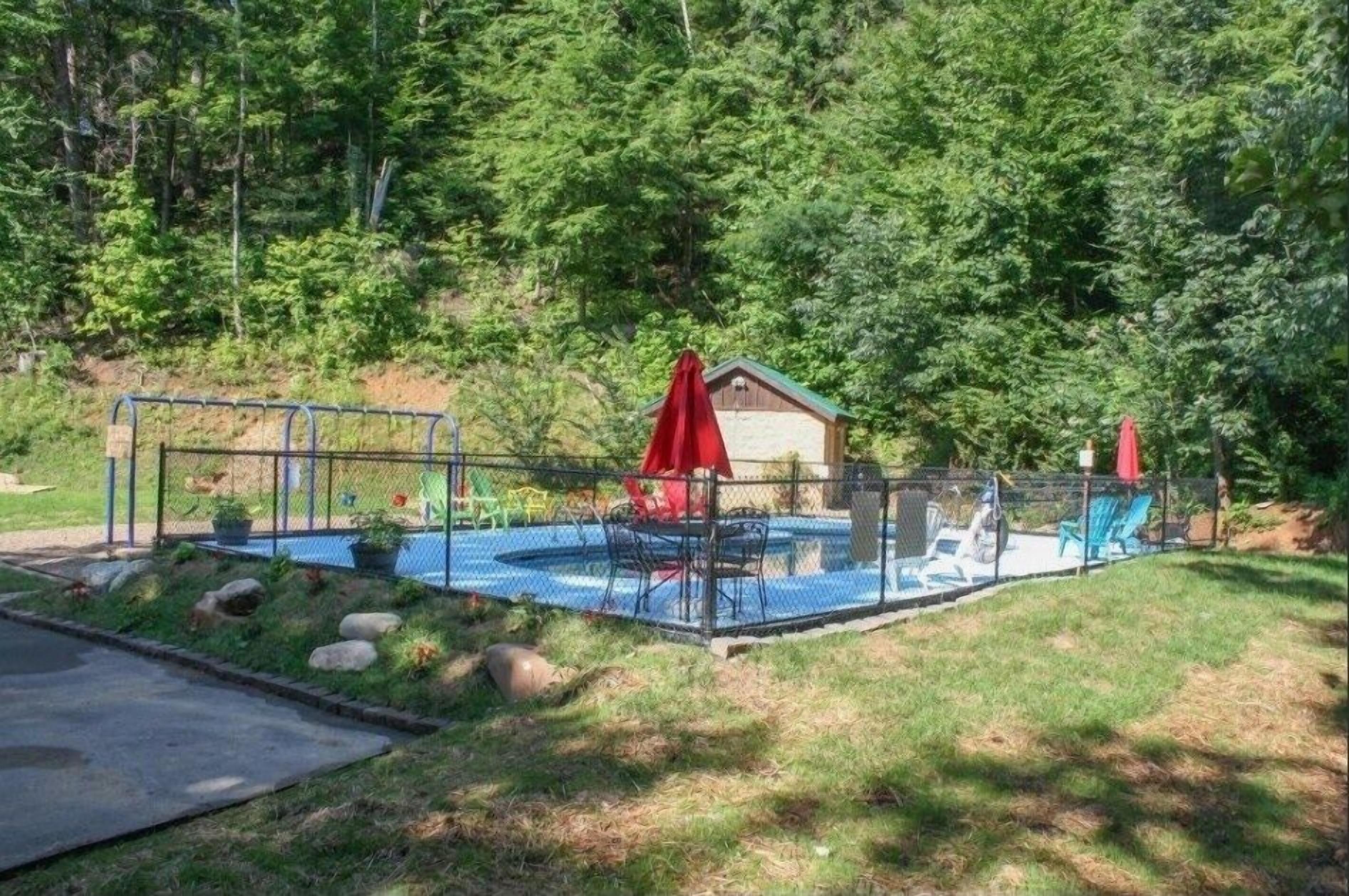 A fenced backyard with a swimming pool, a covered patio area, and a small shed.
