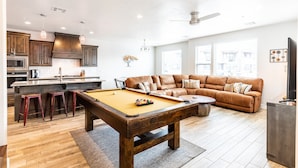 A modern kitchen with wooden cabinets, a pool table, and a cozy living area with a brown leather sofa. - Zion Experience 4 Bedroom Townhouse by RedAwning (Washington)