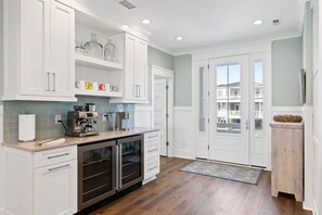 Cocina moderna con armarios blancos, una estación de café y vistas al exterior.