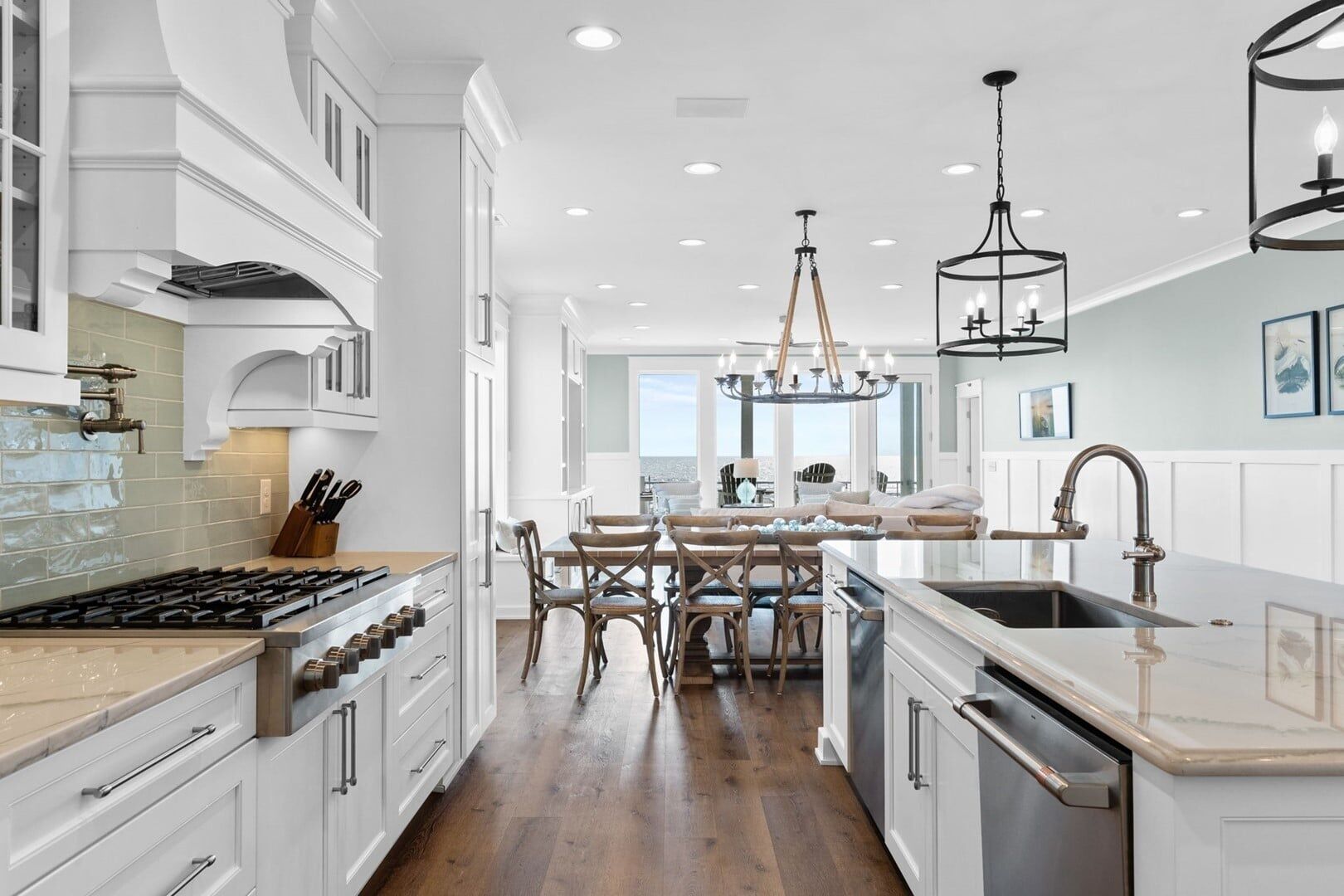 Una cocina moderna con armarios blancos, una isla central y una zona de comedor con sillas de madera.