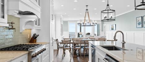Una cocina moderna con armarios blancos, una isla central y una zona de comedor con sillas de madera.